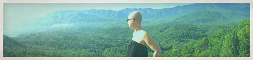 Woman in black dress looking out over a green valley